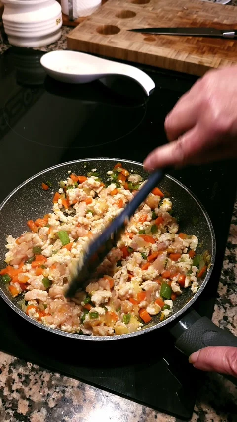 Stirring minced chicken, chopped carrots, and onions in pan. 動画素材 346068425
