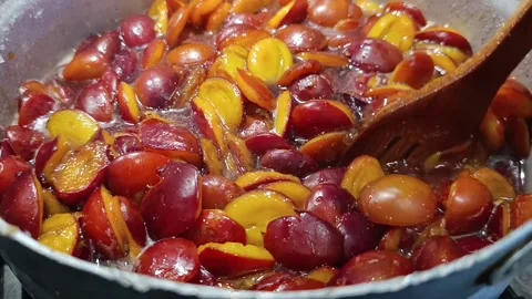 Stirring plum halves in boiling sugar syrup with wooden spoon for jam Stock Footage 344878358