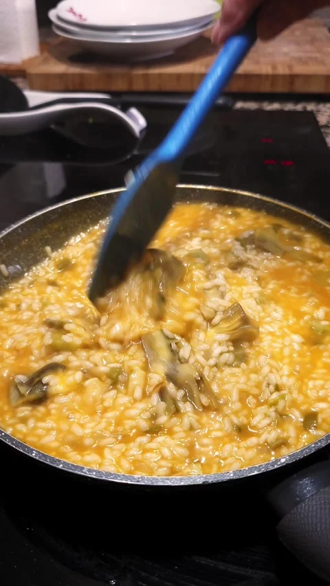 Stirring risotto with artichokes and chicken broth. Stock Footage 345152210