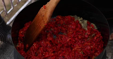 Stirring roasted red pepper with sliced eggplant in a deep pot while making ajva Stock Footage 207717868