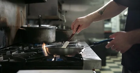 Stirring a sauce over an open flame in a industrial kitchen Stock Footage 105377503