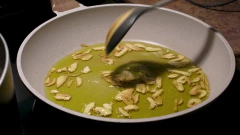 Stirring Sliced Garlic in Hot Olive Oil in Frying Pan Stock Footage 341977394