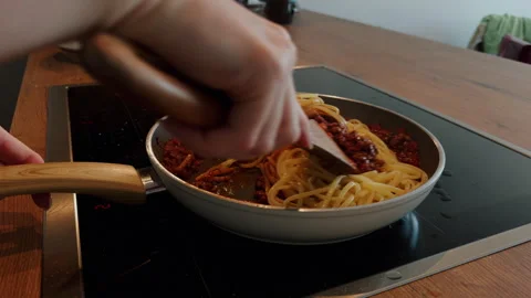 Stirring Spaghetti Bolognese in Pan on Kitchen Hob Induction Plate Stock Footage 339682948