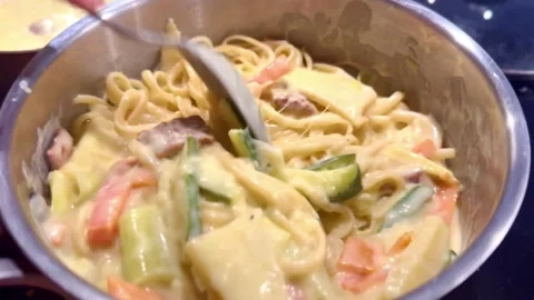 Stirring spaghetti noodles in white mixed creamy carbonara sauce in saucepan Stock Footage 336287178