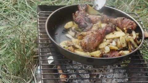 Stirring with a spoon appetizing fried potatoes and chicken drumsticks in a 库存影片 213784532