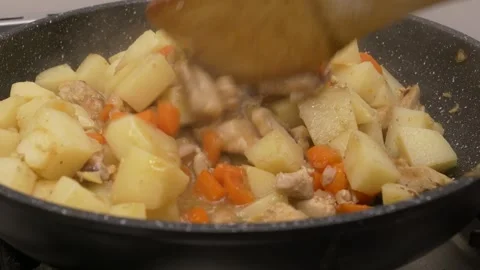 Stirring a stew with chicken chunks, potatoes and carrots in a saucepan 库存影片 291593675