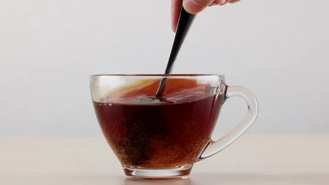 Stirring Sugar into Hot Black Tea in a Clear Glass Cup Stock Footage 345486087
