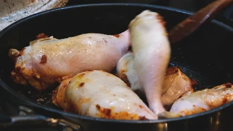 Stirring thai red curry paste into chicken thighs or legs in a frying pan Stock Footage 169505729