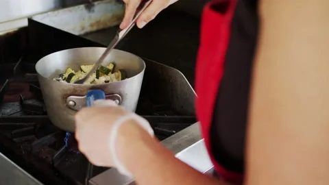 Stirring vegetables on a stove Stock Footage 138470072