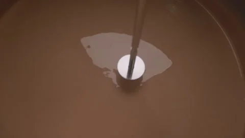 Stirring a viscous brown substance with a mixing rod Vidéo 340336220