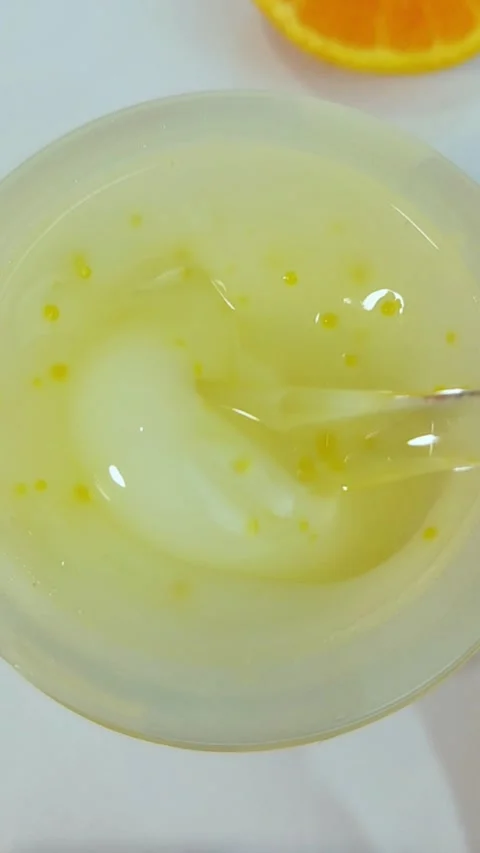 Stirring yellow and white fruit gel serum using a transparent spoon inside .. Vídeos de archivo 330749565