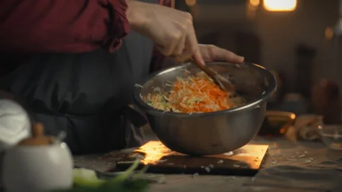 Stirs cabbage with wooden spoon while preparing fresh sauerkraut at home kit Stock Footage 331362136