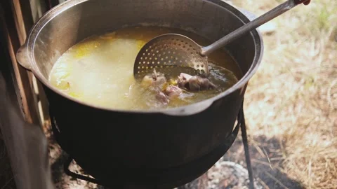 Stirs chop soup in a large fire pit Stock Footage 305305837