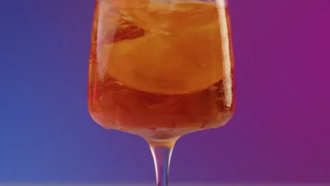 Stirs by straw glass of cold summer cocktail aperol spritz with a beautiful Stock Footage 246738623