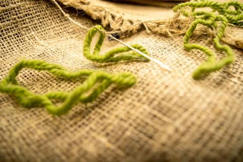 Stitches of green thread on the burlap with a rough texture. Close up. Stock Photos