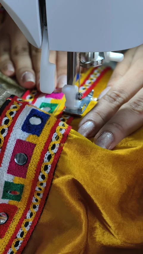 Stitching traditional laces with mirror on a vibrant silk chaniya choli Stock Footage 312744245