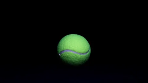 Stock Footage  Dramatic Light Moving Across front of Tennis Ball on Black Ba Stock Footage 249356332