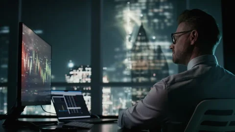 Stock market analyst working at computer desk in front of skyline window Stock Footage 316600424