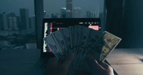 Stock trader analyzing profit chart on laptop, stock trader holding dollar bills Stock Footage 312121901