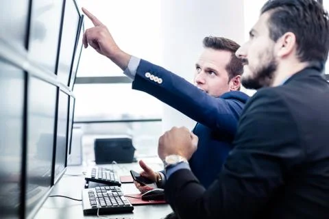 Stock traders looking at market data on computer screens. 写真素材