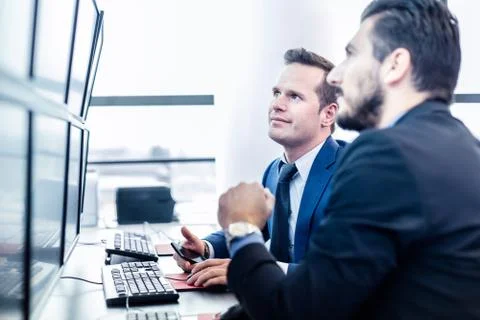 Stock traders looking at market data on computer screens. 写真素材