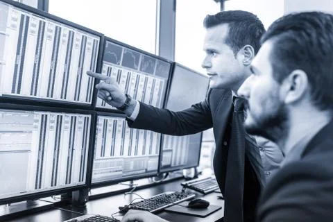 Stock traders looking at market data on computer screens. 写真素材