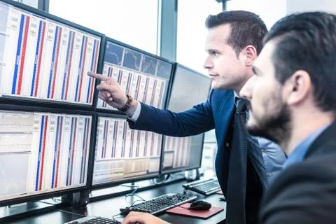 Stock traders looking at market data on computer screens. Stockfoto's