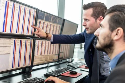 Stock traders looking at market data on computer screens. Stockfoto's
