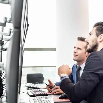 Stock traders looking at market data on computer screens. Successful busin... Stock Photos