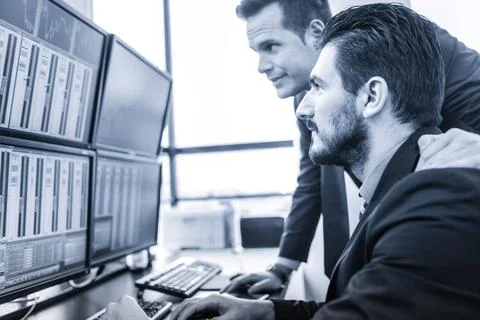 Stock traders looking at market data on computer screens. Businessmen trad... Foto stock