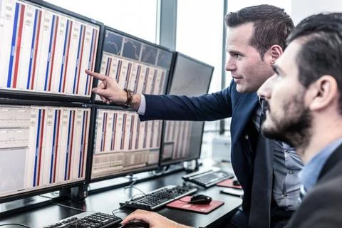 Stock traders looking at market data on computer screens. Businessmen trad... Foto stock