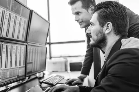 Stock traders looking at market data on computer screens. Businessmen trad... Foto stock