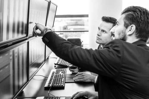 Stock traders looking at market data on computer screens. Businessmen trad... Stock Photos