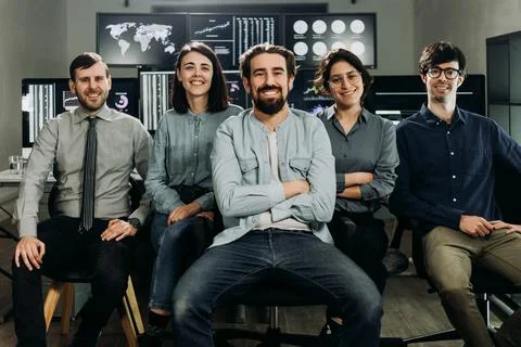 Stock traders smiling in control room with multiple computer screens Stock Photos