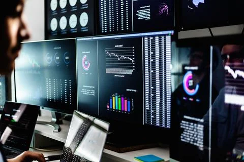 Stock traders working with financial data on multiple computer screens Foto stock