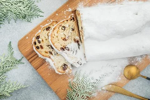 Stollen cake on wooden board, cutlery and gift on gray. Christmas composition Stock Photos