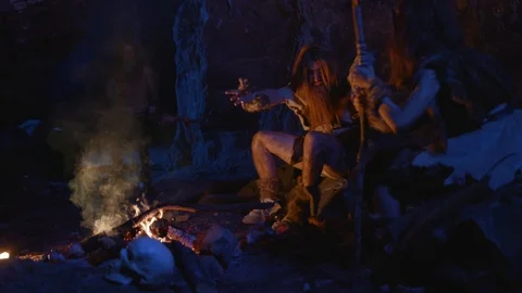 Stone-age ancestors primitive cave people cooking meat on bonfire cheering up at Stock-Footage 116629606
