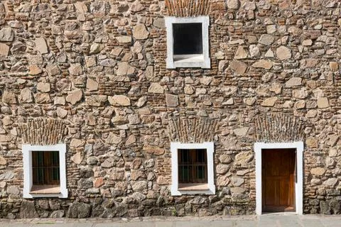 Stone and brick wall with two doors and three windows Stock Photos
