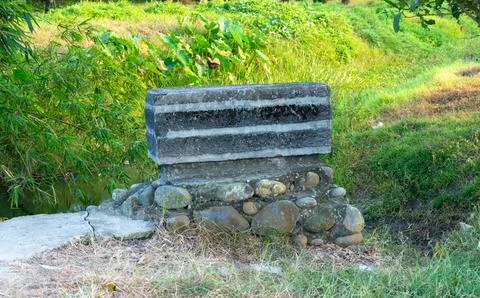 A stone and concrete wall structure stands beside a grassy slope on the edg.. Stock Photos