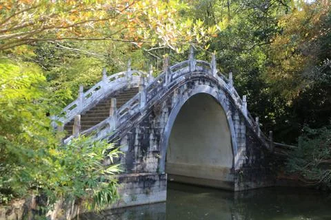 A stone arch bridge over the river in Chinese gardens, with white and gray .. Stock Photos