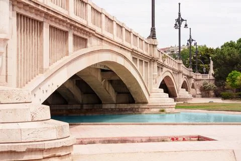 Stone Arch Bridge Over Shallow Urban Canal In Park Foto stock