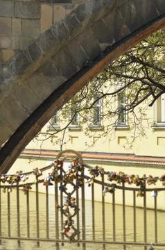 The stone arch of a bridge, with padlocks on the iron framework. Stock Photos