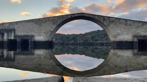 Stone Arch Bridge Reflected in Calm River at Sunset 動画素材 331192898
