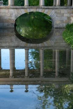 Stone arch bridge reflection on calm palace canal water in summer parkway Stock Photos