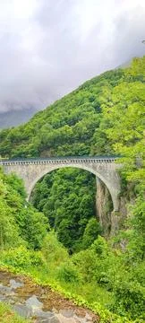 Stone arch bridge spanning a lush green valley in the French Pyrenees, surr.. Stock Photos