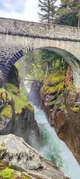 Stone arch bridge spanning a rocky gorge in the French Pyrenees, with rushi.. Stock Photos