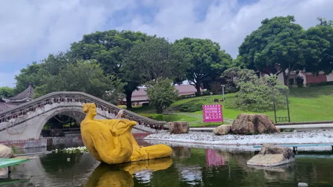 Stone Arch Bridge With Yellow Outdoor Sculpture In A Garden Pond Stock Footage 344240168