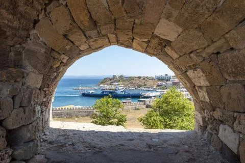 A stone arch frames a stunning view of the harbor where boats are docked. The Stock Photos