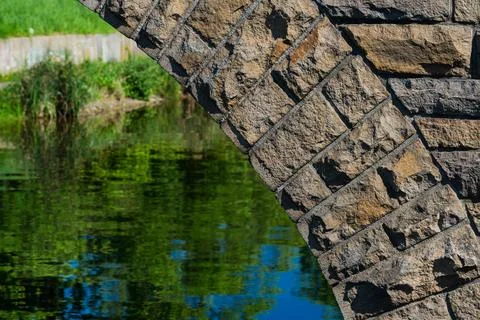 Stone arch with reflection over calm water in a serene location Stock Photos