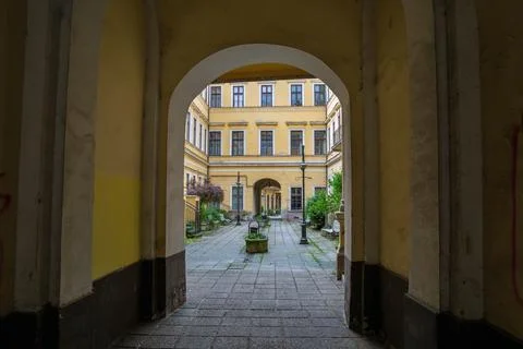 Stone archway frames view of yellow baroque courtyard with symmetrical window Stock Photos